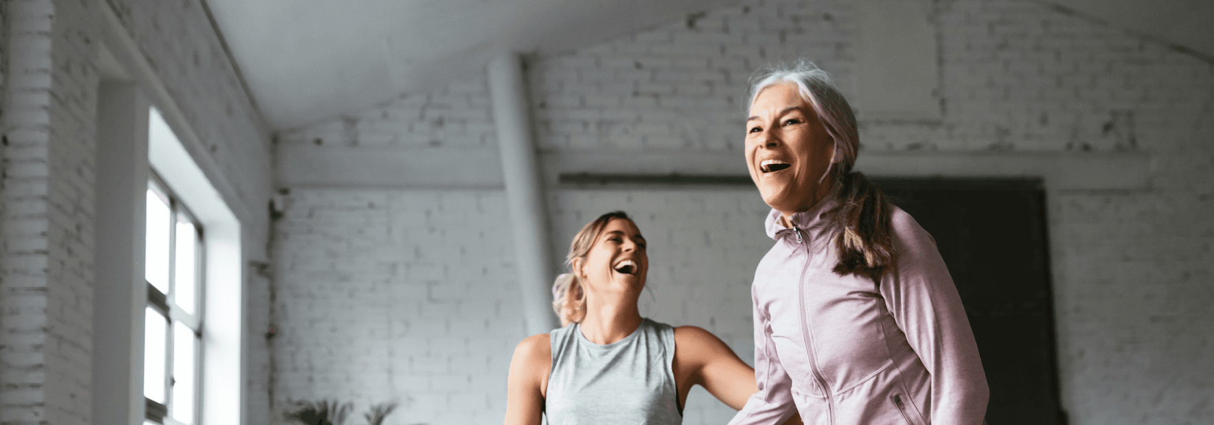 Ayoung woman and an older woman laughing while doing exercises